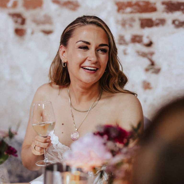 Amelie lacht mit einem Glas Wein in der Hand